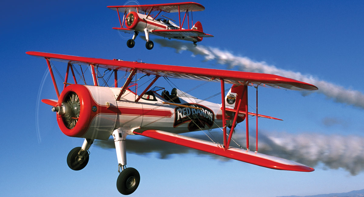 Two Red Barron® bi-planes soar through the sky